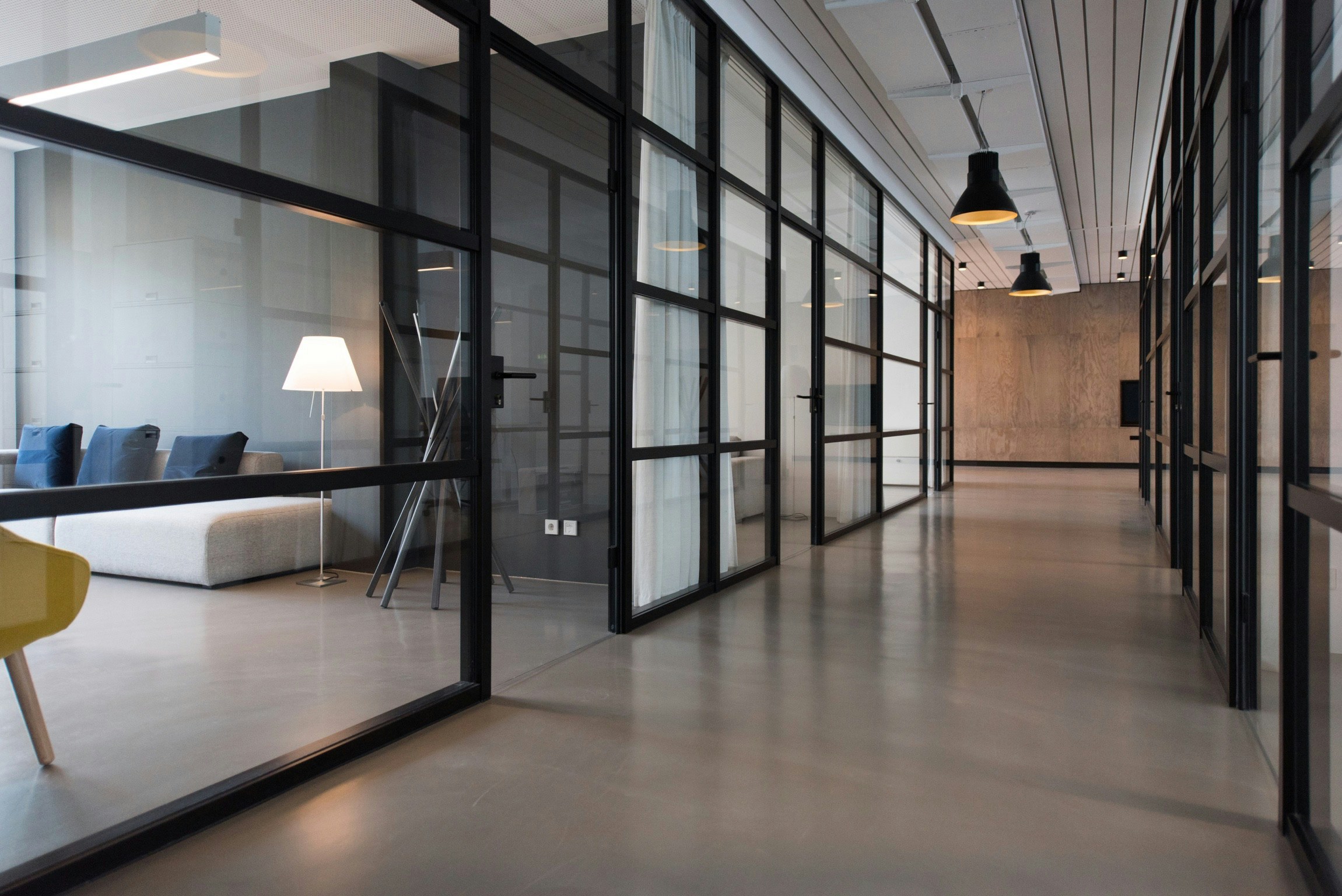 Büroflur mit Glastrennwänden und Loungebereich